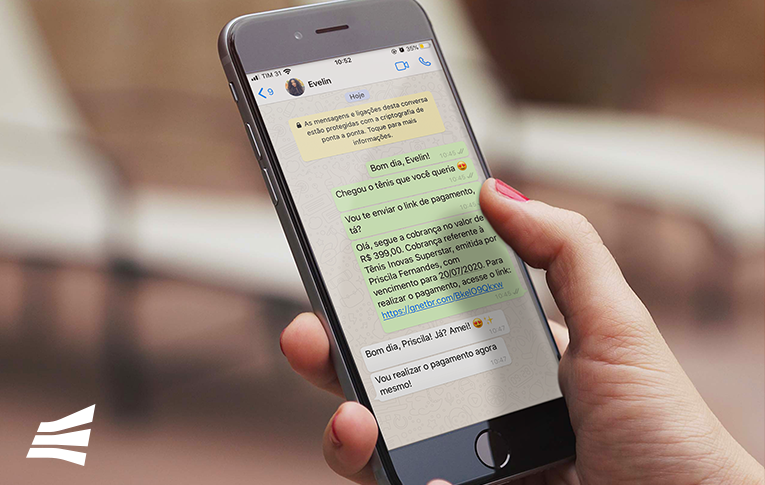 Na imagem: mão feminina segurando um celular com a tela aberta em uma conversa no WhatsAPP, utilizando a ferramenta link de pagamento para emitir uma cobrança