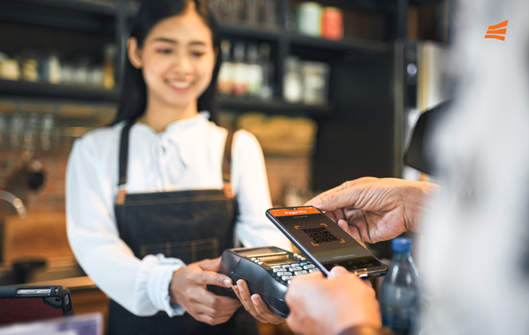 Atendente recebendo pagamento pelo Pix integrado à maquininha de cartão, enquanto o cliente usa o seu smartphone para ler o QR Code