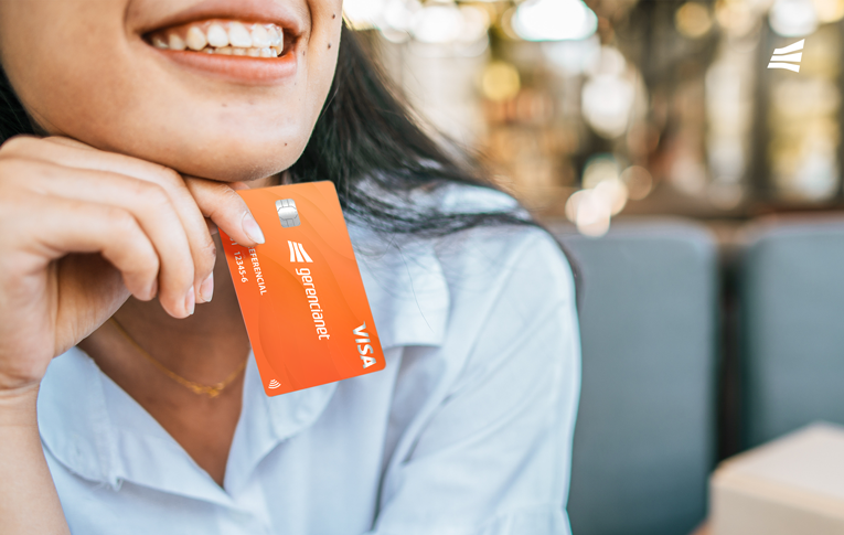 A imagem é um recorte do sorriso e da mão de uma mulher. Na mão ela segura o cartão de crédito Gerencianet.